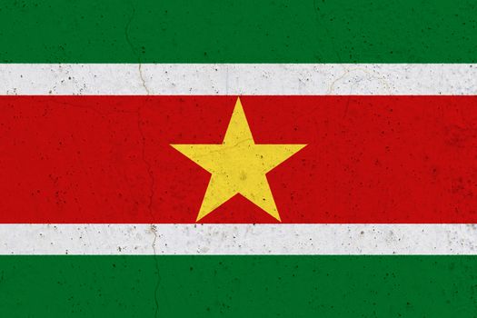 Suriname flag on concrete wall. Patriotic grunge background. National flag of Suriname