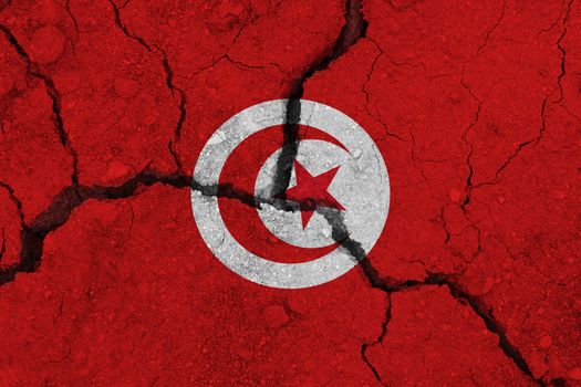 Tunisia flag on the cracked earth. National flag of Tunisia. Earthquake or drought concept