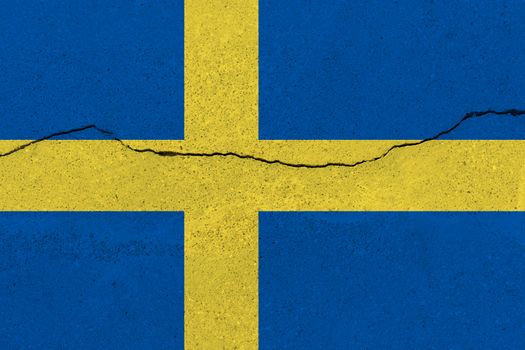 Sweden flag on concrete wall with crack. Patriotic grunge background. National flag of Sweden