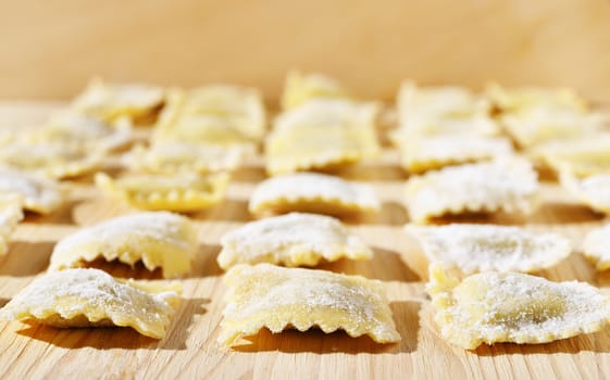 Square ravioli on wooden table , white flour all around ,ravioli on several lines