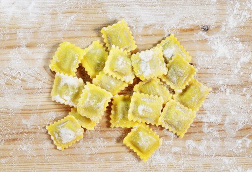 Square uncooked ravioli on wooden table ,white flour all around