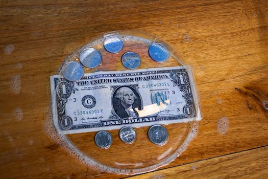 A one dollar bill and coins, all covered by a big bubble