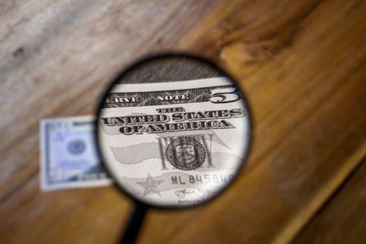 A colorless view through a magnifying glass of the letters, The United States of America, on a one dollar bill. The rest of the images are in color and out of focus.