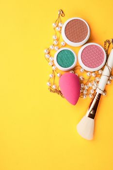 Eyeshadows and makeup brushes on a yellow background top view professional cosmetics. High quality photo