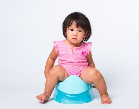 Asian little cute baby child girl education training to sitting on blue chamber pot or potty in, studio shot isolated on white background, wc toilet concept