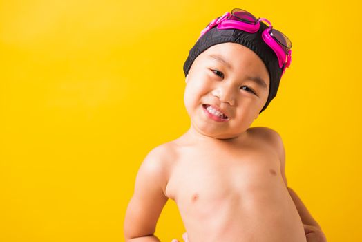 Summer vacation concept, Closeup portrait Asian happy cute little child boy wearing goggles and swimsuit, Kid having fun with in summer vacation looking camera, studio shot isolated yellow background