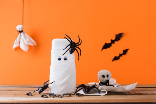 Funny Halloween day decor party concept, The mummy ghost on water glass wrapped around with bandage and have bats and spider stick it found only eyes, studio shot isolated on orange background