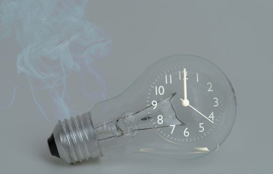 Abstract a light bulb with soot from working and a black analog clock. Show the concept of saving resources on the planet, reducing electricity consumption for future generations.