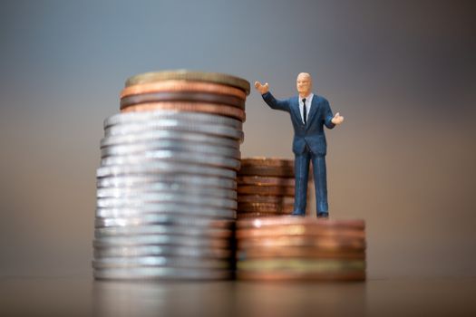 Miniature people: Small businessmen standing with stack of coins , Business Growth concept.