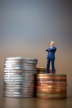 Miniature people: Small businessmen standing with stack of coins , Business Growth concept.