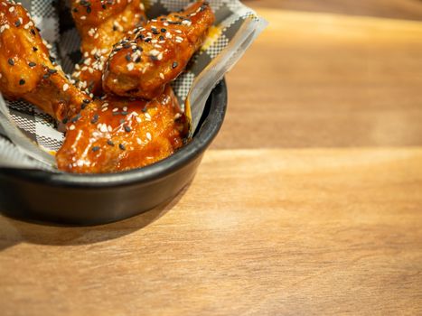 Korean BBQ chicken on a black plate placed on a wooden table background.