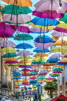 Colorful umbrellas cover a shopping street in Carcassonne, Aude, Occitanie, France