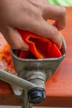 Fresh Ajvar made of tomatoes and paprika on the rustic wooden table. Ajvar with woman hand.