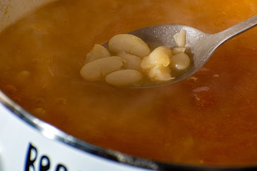 Cookking tasty beans. Closeup of the spoon mixing beans