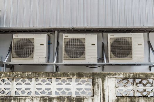 Air compressors hung on the outside wall of the building.