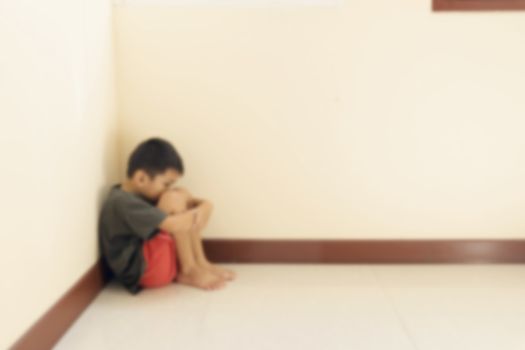 Blurred of the boy hugged her knees in tears in a corner of the room.