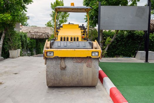 Front view of the steamroller a modern road roller with yellow color.