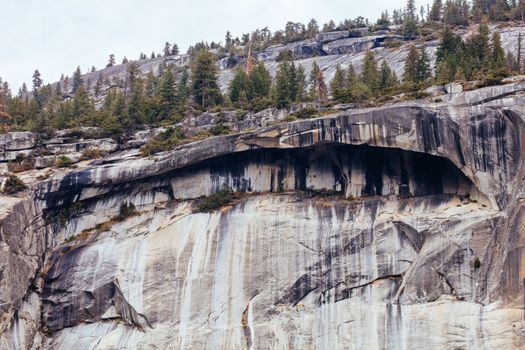 The view from within Yosemite Valley and rock detail of surrounding rock faces on a stormy day in California, USA