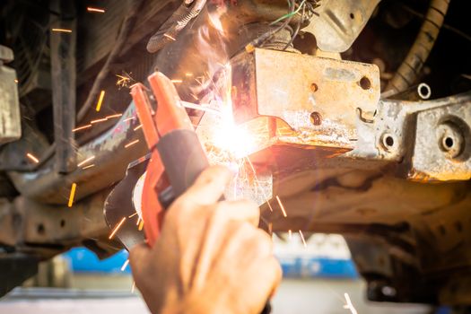 Technician are welding assembly steel under the car in automotive industrial factory -Automotive industry and garage concepts.