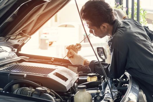 Car mechanic in grey uniform are checking the level of the engine oil, Automotive industry and garage concepts.