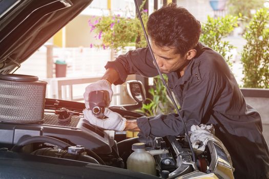 The technician is pouring the engine oil into the engine of the car, Automotive industry and garage concepts.