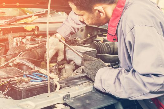 Car mechanic in grey uniform are using a wrench nut at the engine of the car for maintenance, Automotive industry and garage concepts.