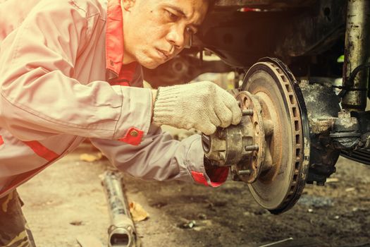 Technicians in grey uniform are repairing the brake of the car, Automotive industry and garage concepts.