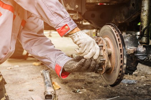 Technicians in grey uniform are repairing the brake of the car, Automotive industry and garage concepts.