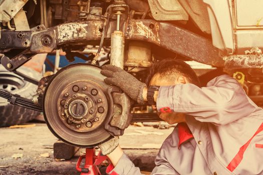 Technicians in grey uniform are repairing the brake of the car, Automotive industry and garage concepts.