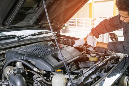 Car mechanic in grey uniform are using a wrench nut at the engine of the car for maintenance, Automotive industry and garage concepts.