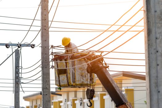 The electrician went up to the crane basket to install the power cord.