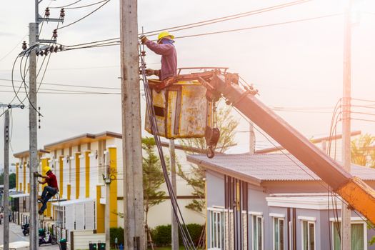 The electrician went up to the crane basket to install the power cord.