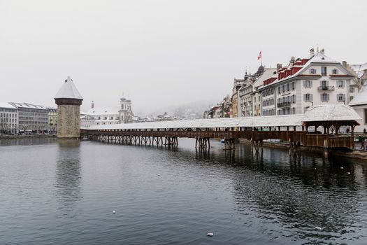 A historic wooden bridge across the river, a landmark in Lucerne, Switzerland.