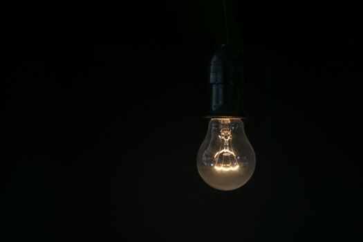 Closeup the incandescent lamp over black background.