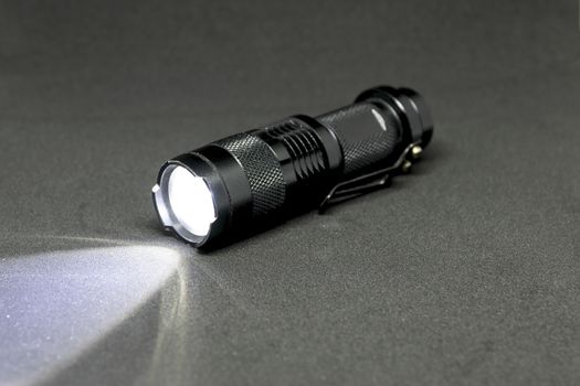 Closeup pocket LED flashlight on dark background.