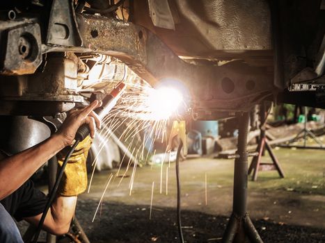 Technician are welding assembly steel under the car in automotive industrial factory -Automotive industry and garage concepts.