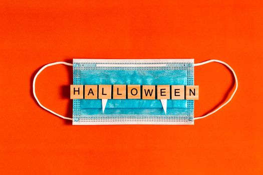 lettering Halloween on a medical protective mask on a black background with silhouettes of bats made of black paper, Halloween 2020 in a new reality. flat layout. Flat lay for your design.