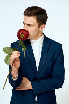 A man in a suit with a rose in his hands a gift date light background. High quality photo