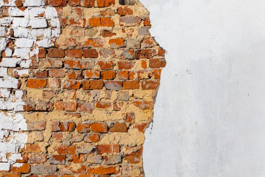 old bad brick wall with leftovers of white peeled thick plaster layer