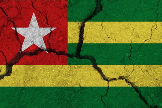 Togo flag on the cracked earth. National flag of Togo. Earthquake or drought concept