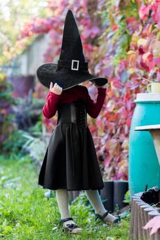 Little girl in witch costume posing on halloween party in the garden