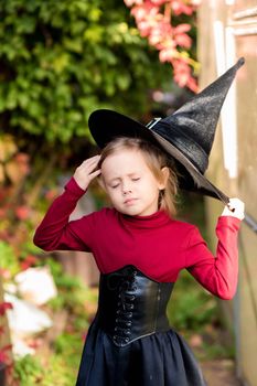 Little girl in witch costume posing on halloween party in the garden.