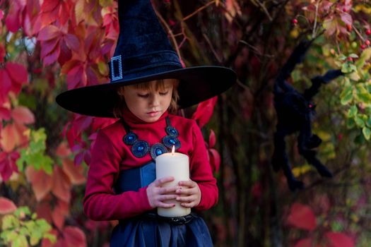 Little girl dressed as a witch holding a candle on a halloween party