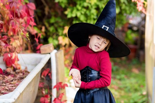 Little girl in witch costume posing on halloween party in the garden.