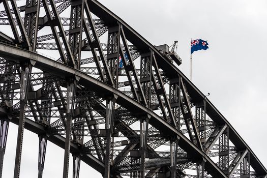 Close-up view of Harbour Bridge steel complex structure and the Australian flag on the top. Sydney, Australia