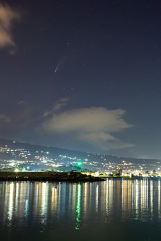 Neowise Comet and its tail from illuminated Riposto harbour near Etna volcano, Sicily, Italy