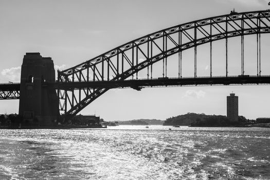 Backlight view of Harbour Bridge silhouette and the bay water from a ferry in a sunny day. Sydney, Australia