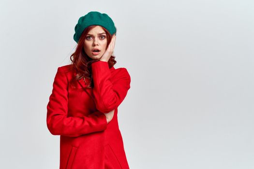 Woman in red coat and in green hat on isolated background cropped model with Copy Space emotions. High quality photo