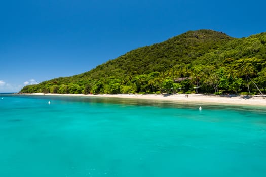 coastline of the tropical Fitzroy Island surrounded by the barrier reef. Vivid colours of a sunny day with blue sky. Queensland, Australia