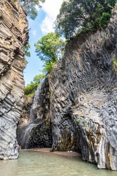 View of basalt rocks, waterfalls and pristine water of Alcantara gorges in Sicily, Italy